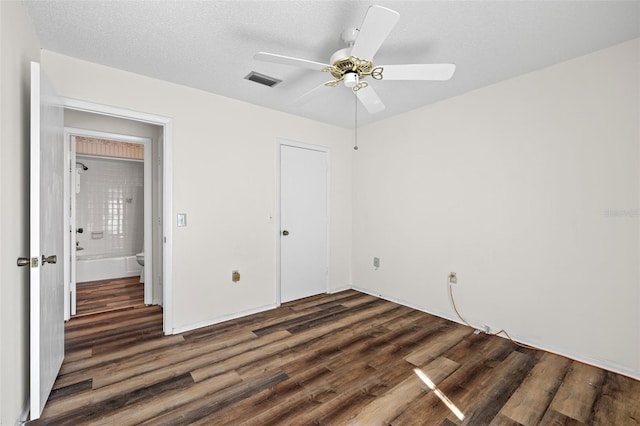 unfurnished bedroom with ceiling fan, a closet, a textured ceiling, and dark wood-type flooring