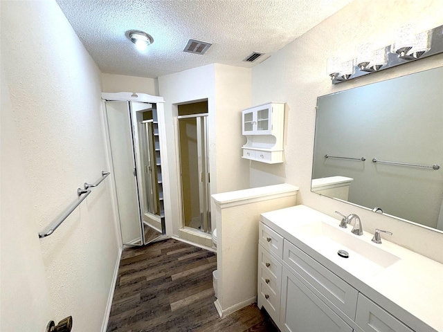 bathroom with vanity, wood-type flooring, a textured ceiling, and walk in shower