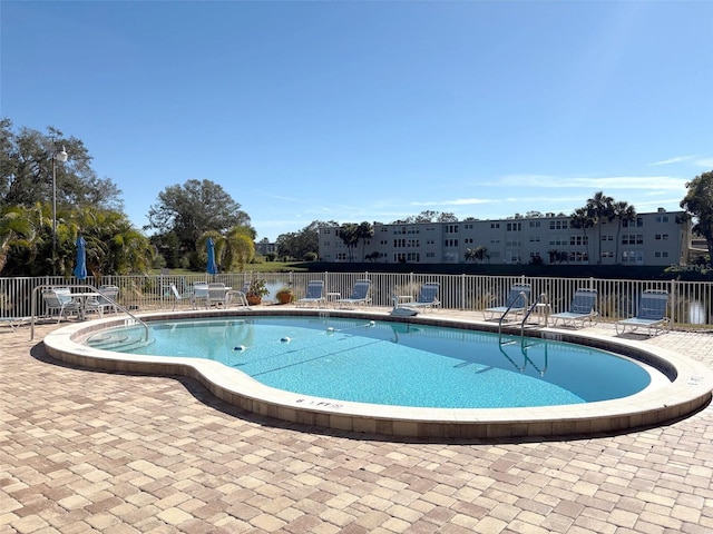 view of pool featuring a patio area and a water view