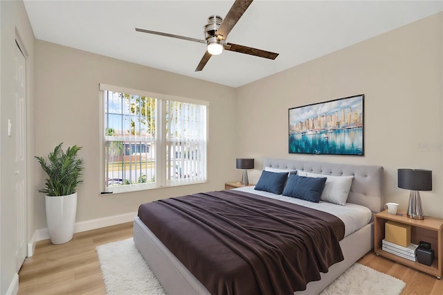 bedroom with light wood-type flooring, ceiling fan, and a closet