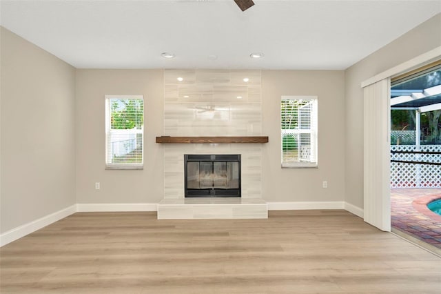 unfurnished living room with light wood-type flooring and a tiled fireplace