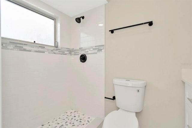 bathroom featuring toilet, vanity, and a tile shower