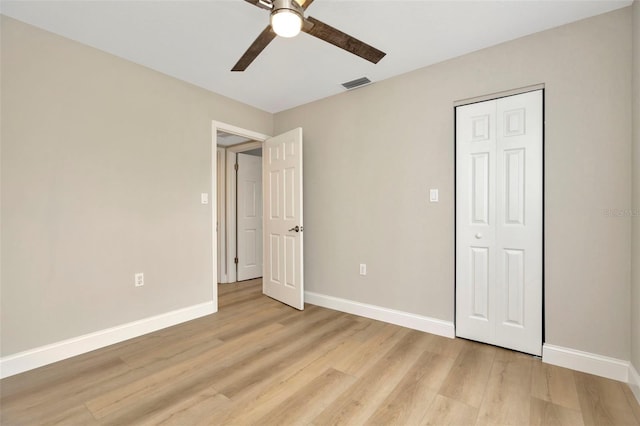 unfurnished bedroom featuring light hardwood / wood-style flooring, ceiling fan, and a closet