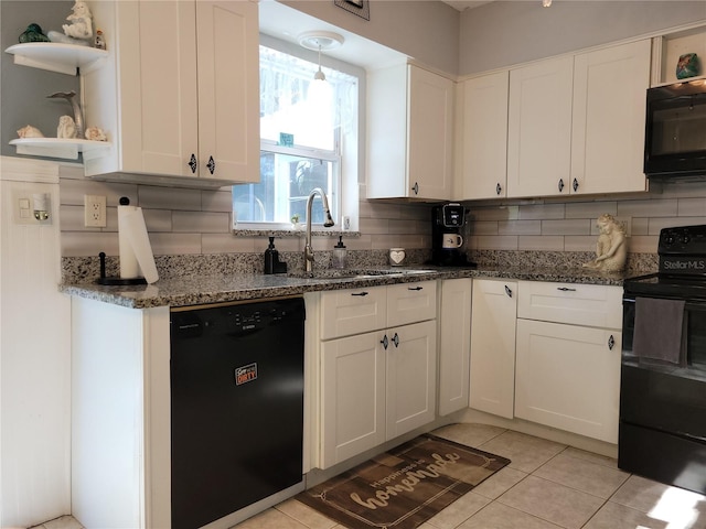 kitchen with black appliances, sink, dark stone countertops, light tile patterned floors, and white cabinetry