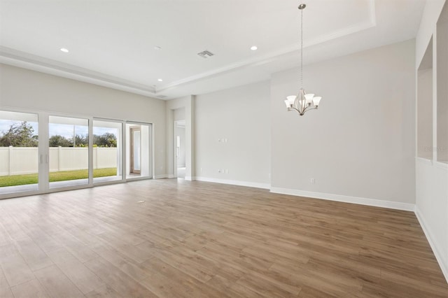 unfurnished living room featuring baseboards, visible vents, a tray ceiling, and wood finished floors