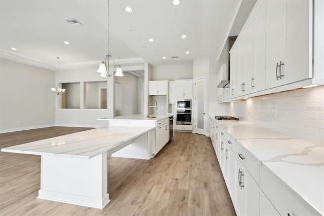 kitchen with a spacious island, white cabinetry, appliances with stainless steel finishes, and decorative light fixtures