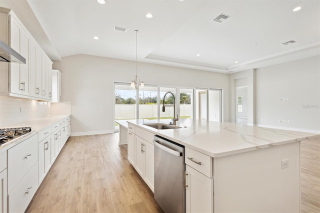 kitchen featuring stainless steel appliances, an island with sink, a sink, and white cabinets