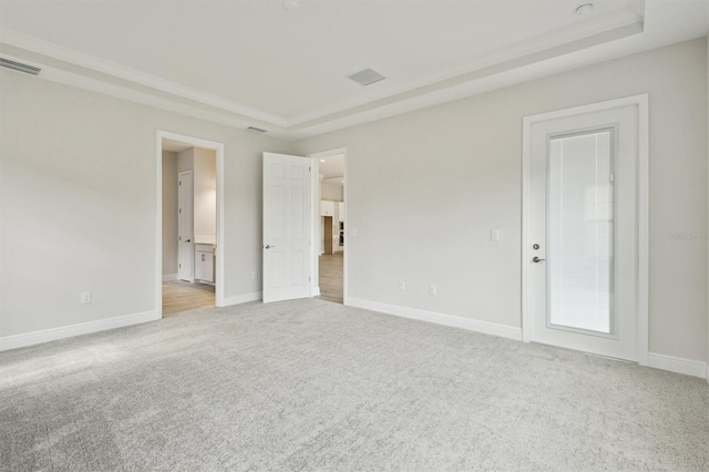 unfurnished bedroom featuring a tray ceiling, light colored carpet, visible vents, and baseboards