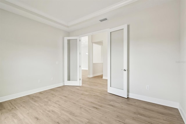 unfurnished room featuring light wood finished floors, visible vents, baseboards, and crown molding