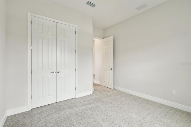 unfurnished bedroom with baseboards, visible vents, a closet, and light colored carpet