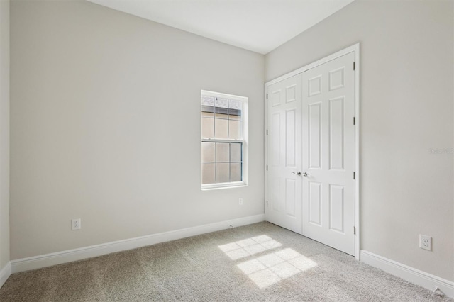 unfurnished bedroom with baseboards, a closet, and light colored carpet