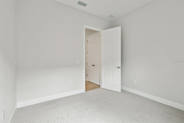 empty room featuring baseboards, visible vents, and light colored carpet