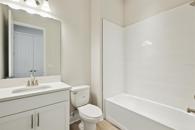 bathroom with toilet, bathing tub / shower combination, wood finished floors, and vanity