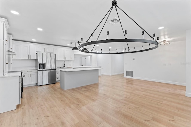 kitchen with white cabinetry, stainless steel refrigerator with ice dispenser, light hardwood / wood-style floors, and a kitchen island