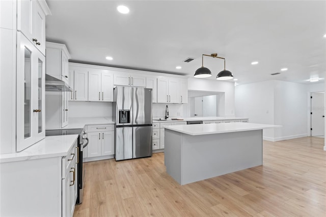 kitchen featuring stainless steel appliances, light hardwood / wood-style floors, sink, decorative light fixtures, and white cabinets