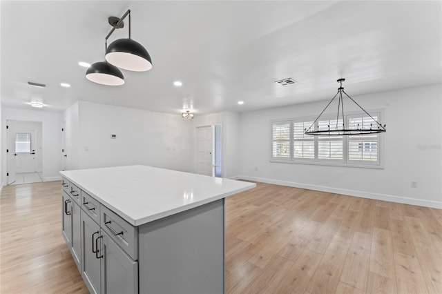 kitchen featuring gray cabinets, light wood-type flooring, hanging light fixtures, and a notable chandelier