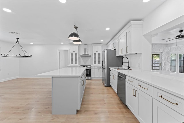 kitchen featuring stainless steel appliances, sink, light hardwood / wood-style flooring, a center island, and white cabinets