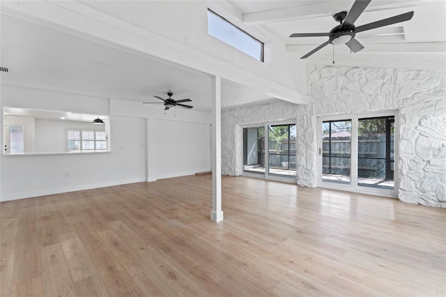 unfurnished living room featuring ceiling fan, beamed ceiling, a healthy amount of sunlight, and light hardwood / wood-style flooring