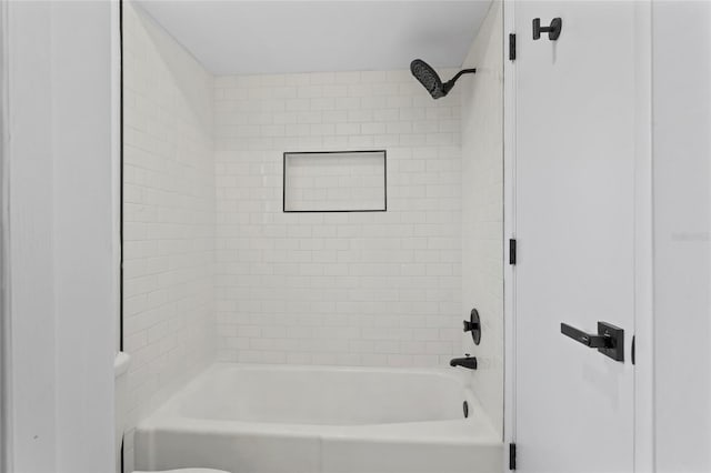 bathroom featuring tiled shower / bath and toilet