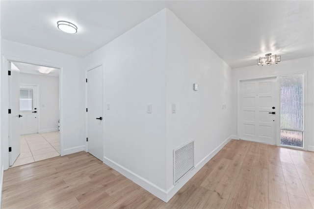 foyer entrance with light hardwood / wood-style flooring and a chandelier