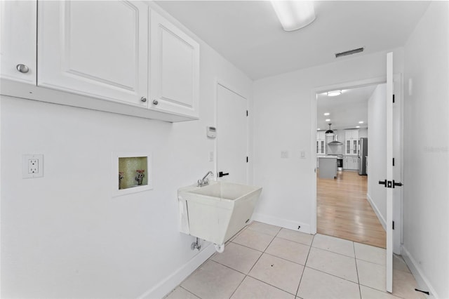 laundry area with washer hookup, cabinets, sink, and light tile patterned floors