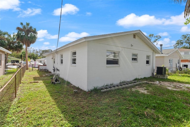 view of side of home with central AC and a lawn