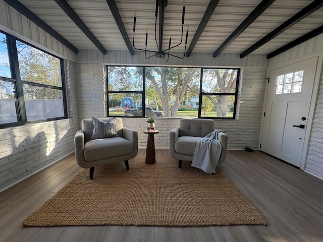 sitting room with beamed ceiling, wood-type flooring, wooden walls, and brick wall