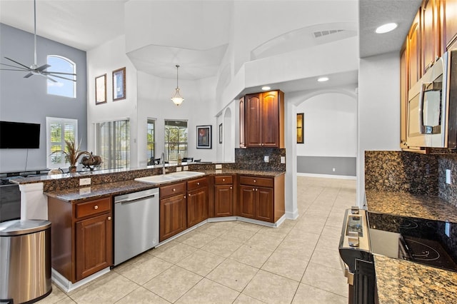 kitchen with appliances with stainless steel finishes, sink, a high ceiling, and light tile patterned floors