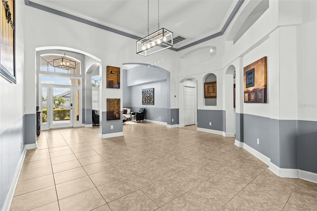 interior space featuring a high ceiling, a chandelier, and crown molding