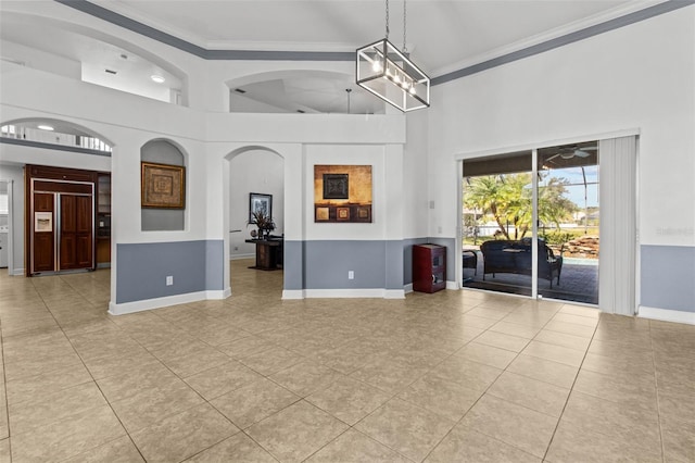 tiled spare room with crown molding, a notable chandelier, and a high ceiling