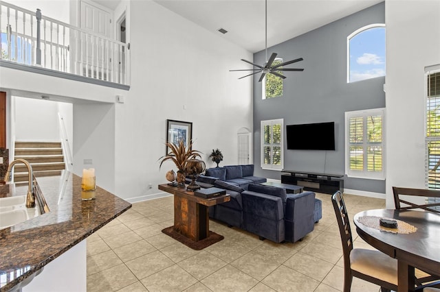 living room with a high ceiling, ceiling fan, light tile patterned floors, and sink