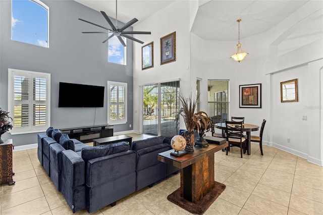 living room featuring a wealth of natural light, ceiling fan, a high ceiling, and light tile patterned floors