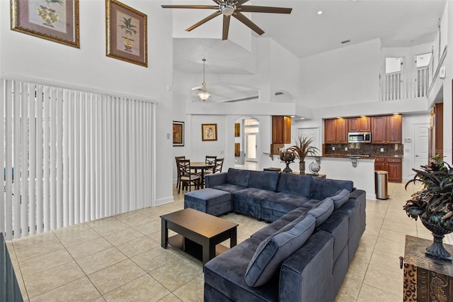 tiled living room with ceiling fan and high vaulted ceiling