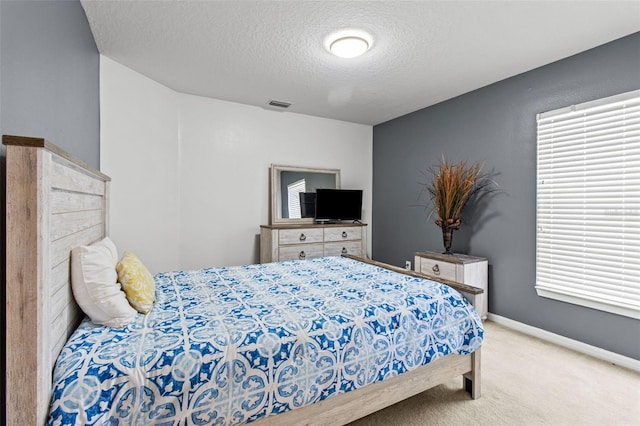 bedroom featuring light colored carpet and a textured ceiling