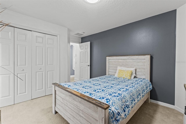 carpeted bedroom with a textured ceiling and a closet