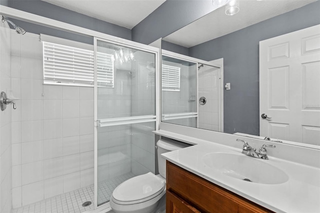 bathroom featuring toilet, vanity, and a shower with door