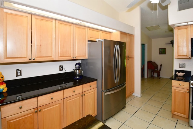 kitchen featuring light brown cabinets, dark stone counters, light tile patterned floors, and stainless steel fridge