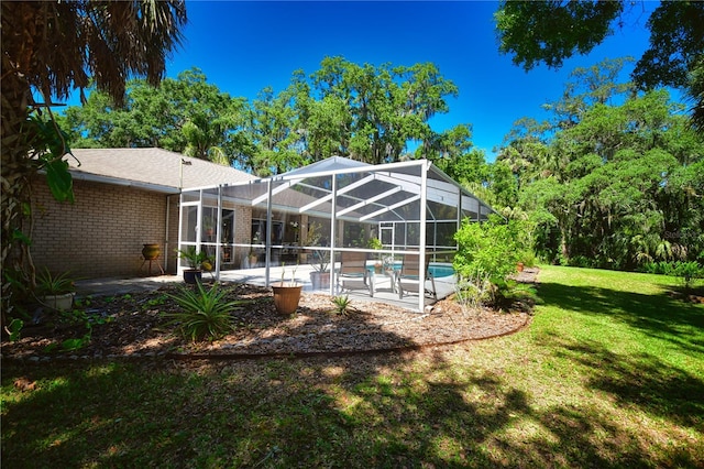 rear view of property featuring a lanai, a lawn, and a patio