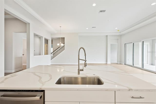 kitchen with dishwasher, hanging light fixtures, light stone countertops, white cabinetry, and a sink