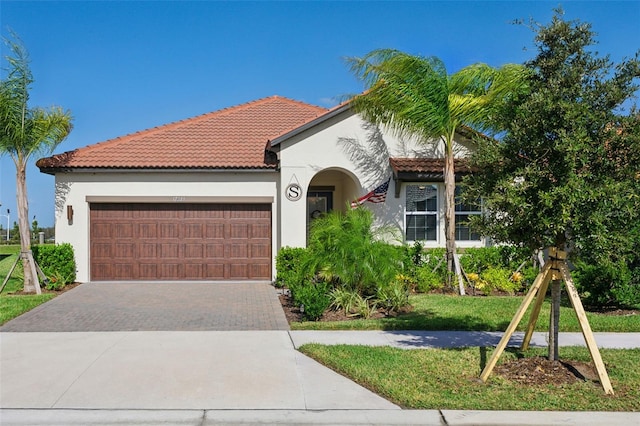 mediterranean / spanish home with a garage and a front lawn