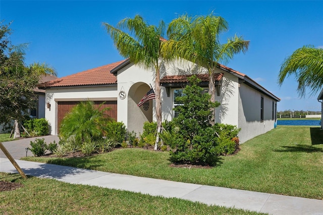 mediterranean / spanish house featuring a front yard and a garage