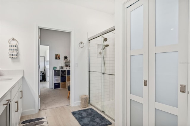 bathroom with vanity, washer / clothes dryer, and a shower with door