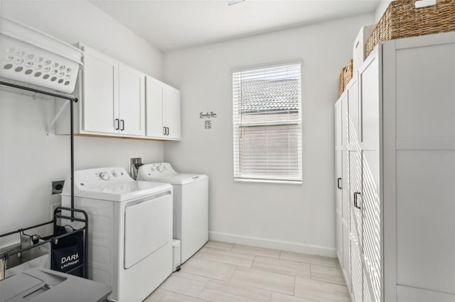 clothes washing area with cabinets and separate washer and dryer