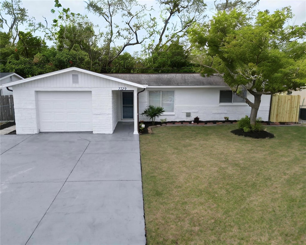 single story home featuring a garage, a front yard, brick siding, and driveway