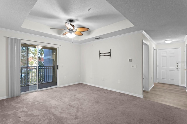 carpeted spare room with a textured ceiling, crown molding, a tray ceiling, and ceiling fan