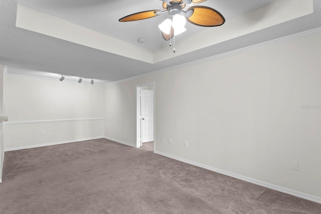 spare room featuring a tray ceiling, carpet flooring, ceiling fan, and crown molding