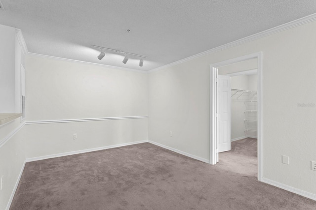 carpeted empty room featuring rail lighting, a textured ceiling, and ornamental molding