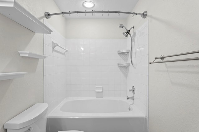 bathroom featuring tiled shower / bath combo and toilet