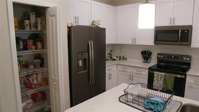 kitchen with white cabinets, appliances with stainless steel finishes, decorative backsplash, and light stone counters