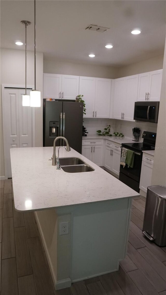 kitchen featuring refrigerator with ice dispenser, hanging light fixtures, an island with sink, and black / electric stove